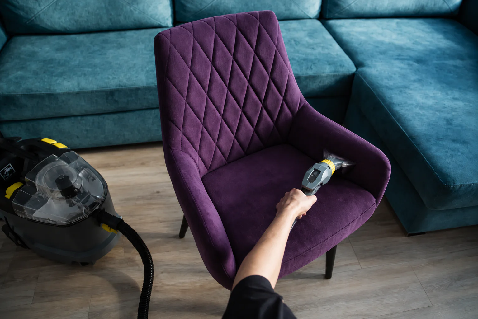 Professional upholstery cleaning on a purple armchair beside a teal sofa